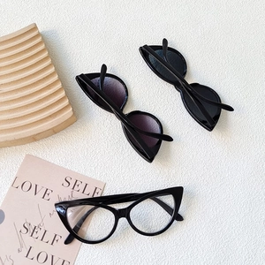 Close-up of three cat-eye kids sunglasses on a textured surface with wooden accents