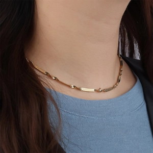 Detailed close-up of a gold-plated twisted snake chain necklace worn on a neck