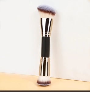 Detail of dual-ended makeup brush with gold ferrule and white-brown gradient bristles