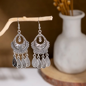 Bohemian hollow metal earrings with water-drop charms hanging on natural wood