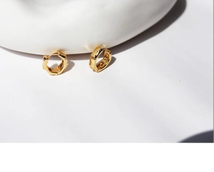 Close-up of golden hoop earrings featuring a minimalist textured bamboo style design