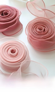 Top view of layered pink gradient organza ribbons with wavy fishtail edges for gift wrapping