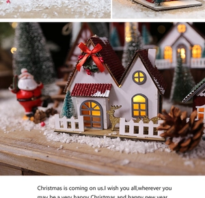 Detail of DIY lighted wooden Christmas house with red roof and warm yellow LED glow