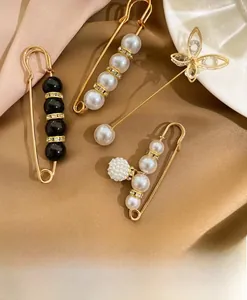 Detail of four golden alloy pearl brooches and rhinestone pins on silk fabric