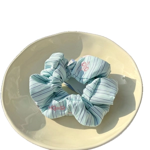 Blue twill scrunchie with pink embroidery and star academy style displayed on a plate