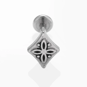 Vue macro d'un piercing losange argenté avec des motifs floraux en relief
