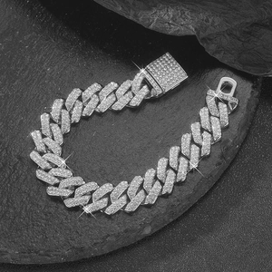 Macro shot of silver-colored iced out Cuban chain bracelet with CZ diamonds on black rock