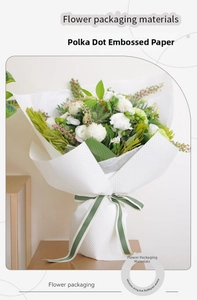 Detail of white 3D embossed polka dot flower wrapping paper with decorative green ribbon