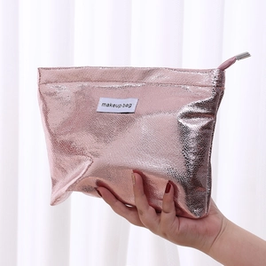 Close-up of a pink metallic texture makeup bag held by hand against a white backdrop