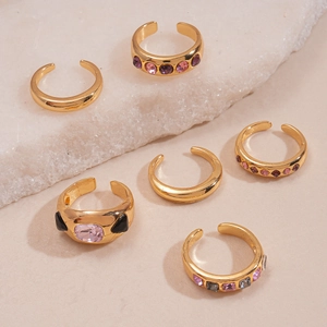 Set of 6 gold geometric open rings with colorful rhinestones on a white stone base