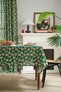 Detail of green linen Christmas tablecloth featuring festive gingerbread and snowman patterns