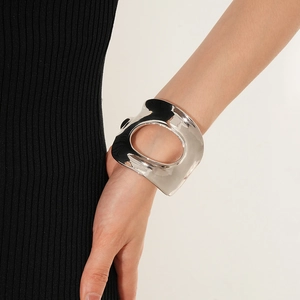 Gros plan détaillé d'un large bracelet manchette argenté ajouré porté par un mannequin