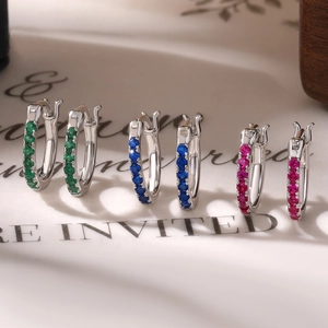 Close-up of 925 silver huggie earrings featuring green, blue, and pink cubic zirconia