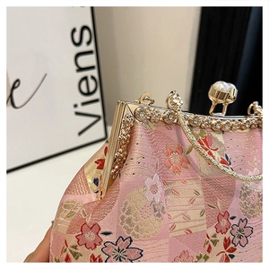 Detail of pink embroidered evening bag with gold metal frame and pearl clasp closure