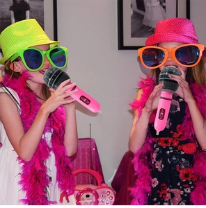 Close-up of kids holding a pink inflatable toy microphone during a vibrant fun party