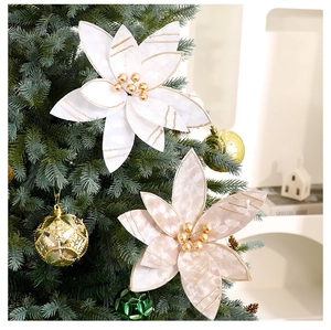 Close-up of velvet cream Christmas flower with gold beads on green tree branches