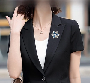 Detail of blue enamel flower brooch with white pearl on a black suit lapel