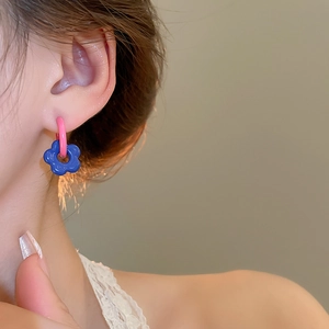 Detail of sweet asymmetrical flower earring with pink metal ring and blue enamel petal pendant