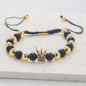 Detail of adjustable beaded bracelet featuring matte black stones and a gold crown pendant