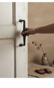 Close-up of vintage cast iron black handle installed on a white weathered wooden door