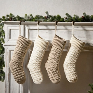 Set of 4 knitted Christmas stockings in beige and cream hanging on a vintage white fireplace