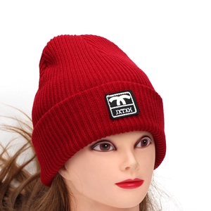 Classic red ribbed knit beanie for women featuring a small black logo patch on the folded cuff