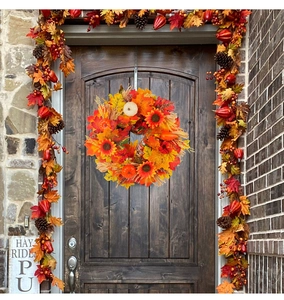 Close-up of harvest wreath with pumpkins and sunflowers on a dark wooden door