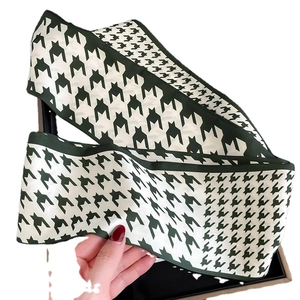 Fashionable houndstooth pattern silk scarf in green and white being held by hand