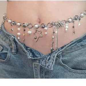 Detail of silver Y2K waist chain with white pearls and star charms on denim jeans