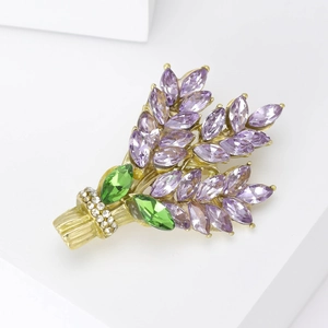 Detailed close-up of lavender brooch with purple crystals and gold finish on white blocks
