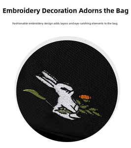 Detailed close-up of white rabbit and flower embroidery on black fabric backpack