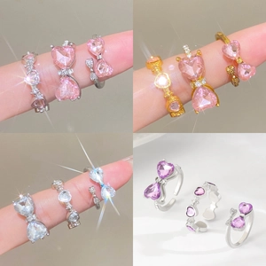 Detail of adjustable heart ring with bow and colorful zircons on finger
