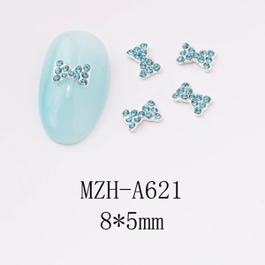 Macro detail of 8x5mm light blue rhinestone bow nail art charm with silver metal base