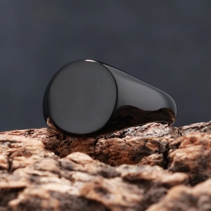 Macro view of polished black signet ring on rustic wood bark with smooth mirror finish