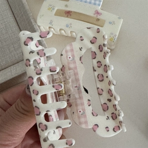 Detailed view of large floral bow hair claws with pink leopard print and grid patterns