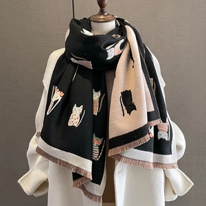Cashmere-like knit scarf with cat patterns and tassels shown on a white coat display