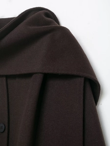 Detailed view of the dark brown wool coat texture and a sleek black button fastener