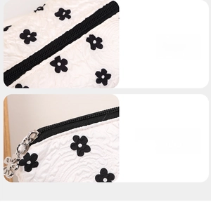 Close-up of smooth black zipper with flower pendant and neat stitching on floral pouch