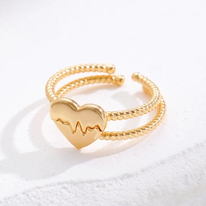 Close-up of golden heart ring with EKG engraving and twisted double-layer band detail