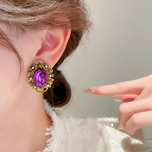 Close-up of vintage purple oval gem earring with golden base and tiny pearls