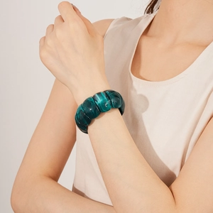 Close-up of a dark green marble acrylic bracelet on model's wrist with polished finish