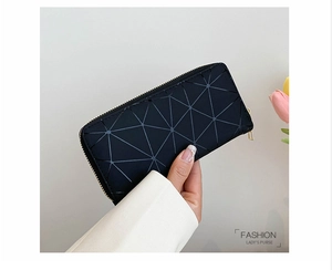 Detail of black long wallet featuring geometric triangle patterns and a gold zipper closure