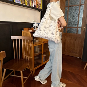 Detailed close-up of a white tote bag featuring purple butterfly jacquard and fringe edges