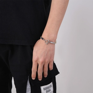 Detail von silber-goldener Gliederkette mit Herz-OT-Verschluss am Handgelenk des Models