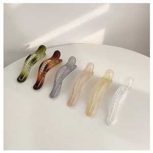 Collection of six matte-finish hair clips in green, brown, and pastel tones on white surface
