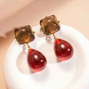 Vue détaillée de boucles d'oreilles carrées ambre et goutte rouge en métal doré