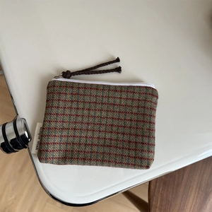 Detail of colorful tweed plaid mini pouch with a zipper closure and textile label