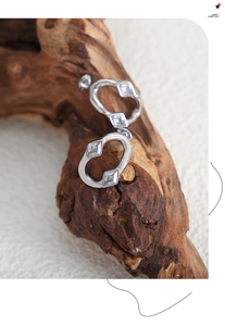 Macro detail of irregular silver earrings featuring cubic zirconia set on natural wood