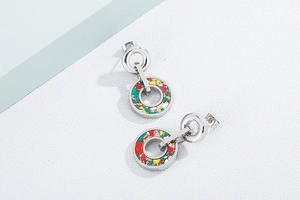 Close-up of silver steel earrings with vibrant multi-colored resin inlay and artistic design