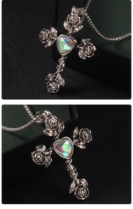 Close-up of gothic cross necklace featuring a rose detail and heart-shaped iridescent gem
